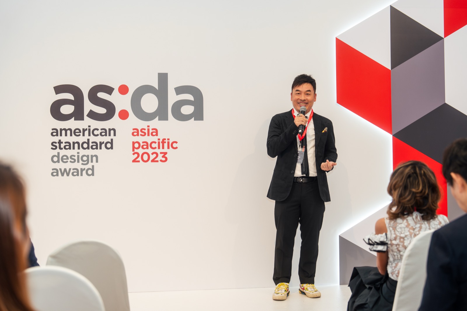 Speaker presenting beside the American Standard Design Award Asia Pacific 2023 wall
