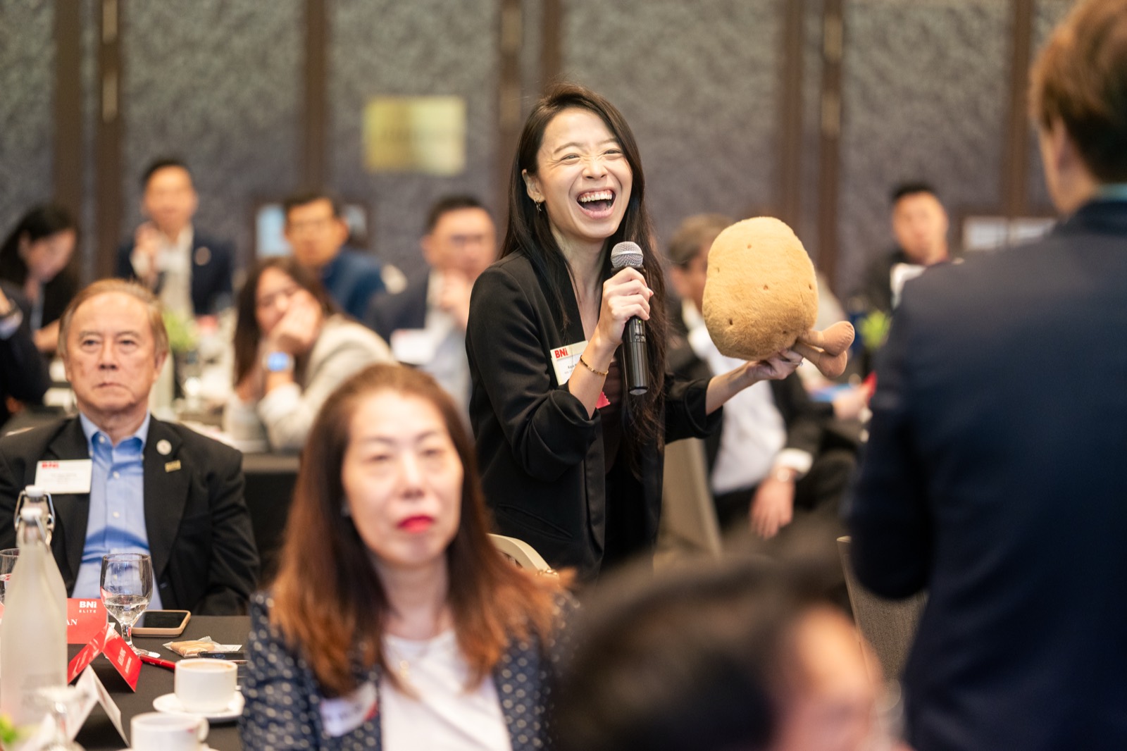 Guest laughing while asking a question at a BNI ballroom session in Singapore