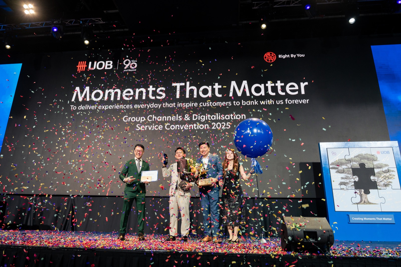 Award winners celebrating on stage under falling confetti at the UOB service convention at Suntec Singapore